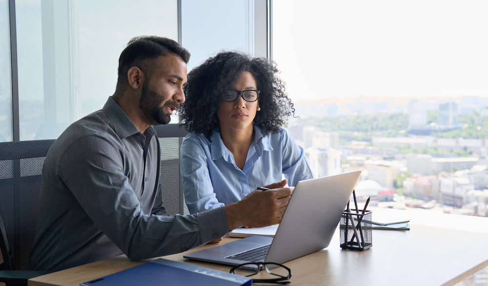 Businesswoman and man sharing ideas at a desk with a laptop